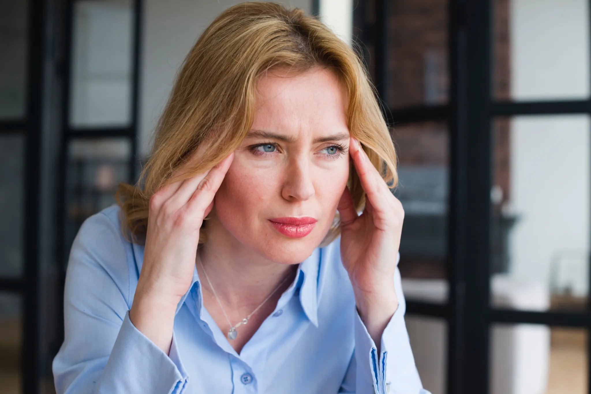 Mujer con expresión de cansancio y tensión mental, representando la carga invisible y el agotamiento de la maternidad moderna. "Me siento la peor madre defl mundo"