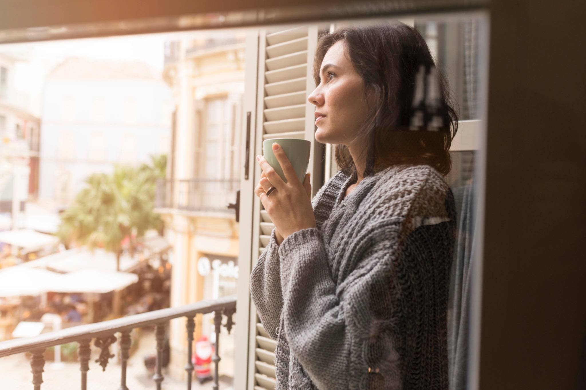 Mujer reflexiva junto a una ventana con una taza en las manos, simbolizando la toma de conciencia en la crianza.