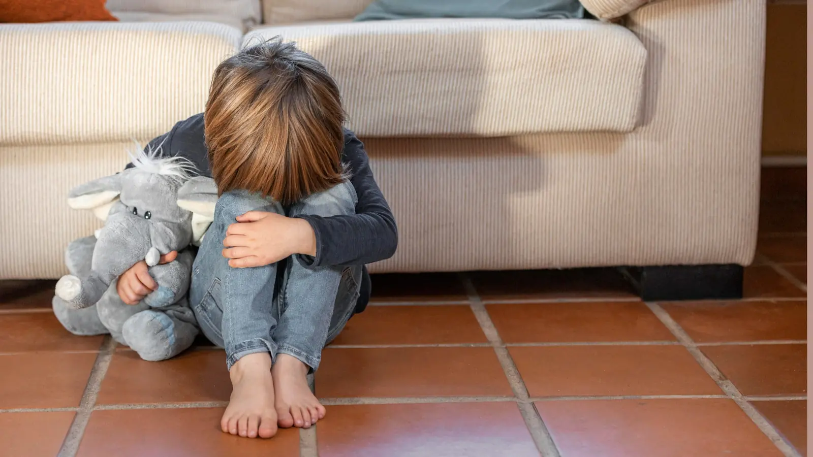 Tratar mal a un hijo deja huellas no siempre visibles
Niño sentado en el suelo abrazando su peluche en actitud de desbordamiento emocional 

