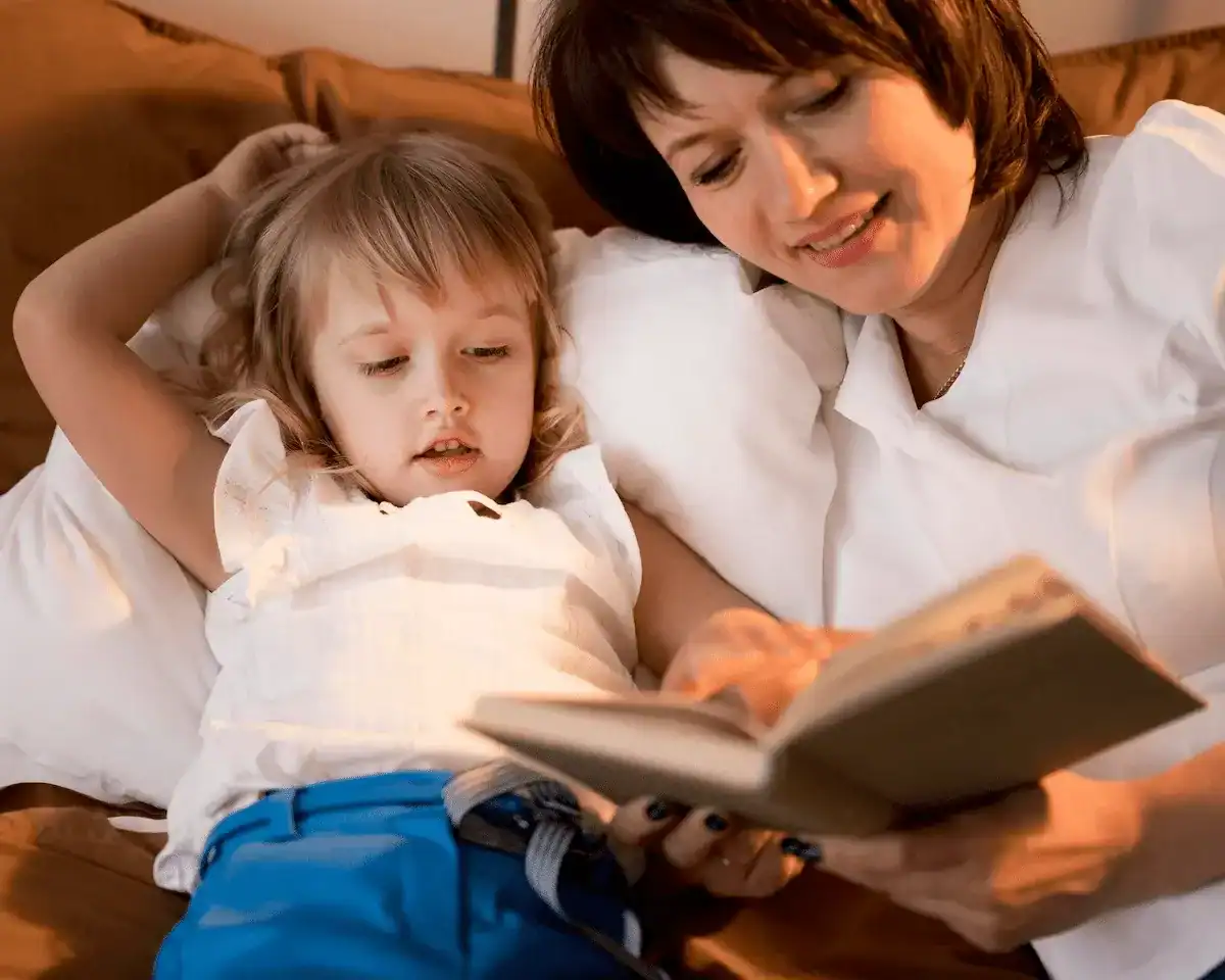 cambio de hora en los niños necesita una rutina tranquila antes de dormir niño leyendo cuento con adulto