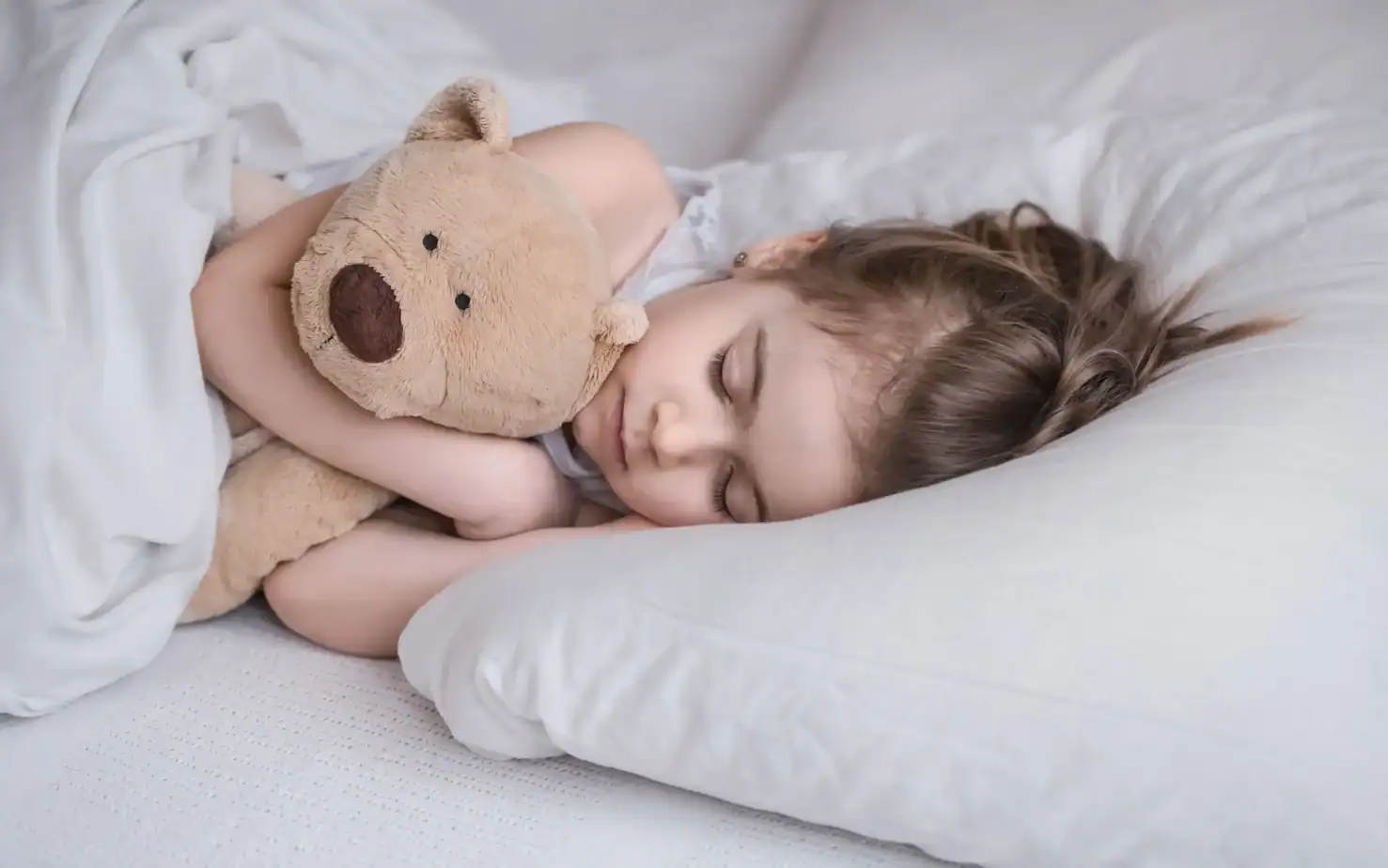 niña durmiendo tranquila abrazando un peluche en un entorno seguro