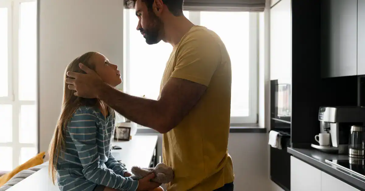 Padre mirando a su hija con expresión de preocupación, ilustrando el miedo que hay detrás de la sobreprotección parental.