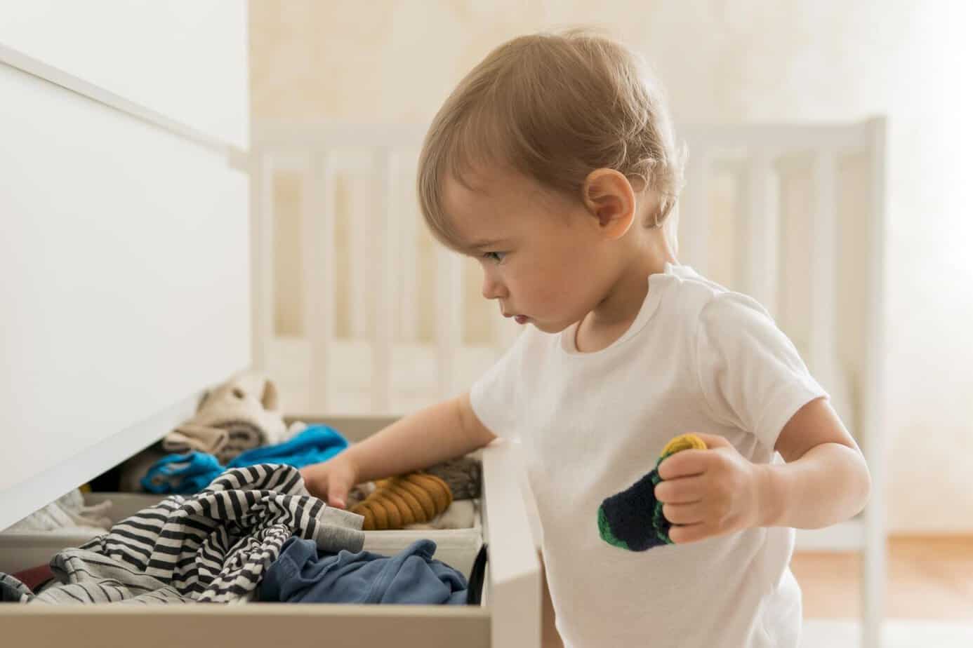 Niño buscando ropa en el cajón antes de vestirse por la mañana