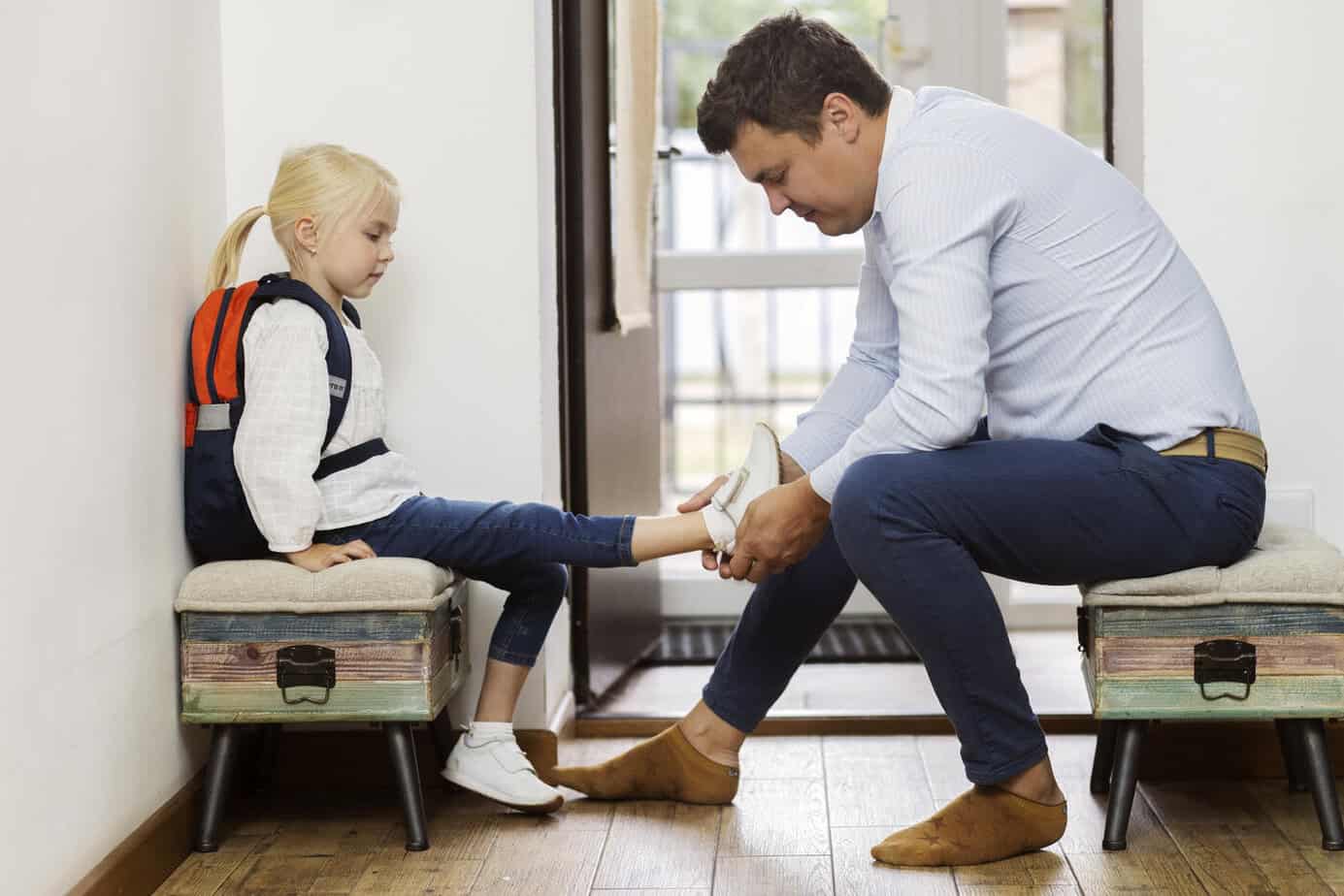 Padre ayudando a su hija a ponerse los zapatos en la rutina matutina