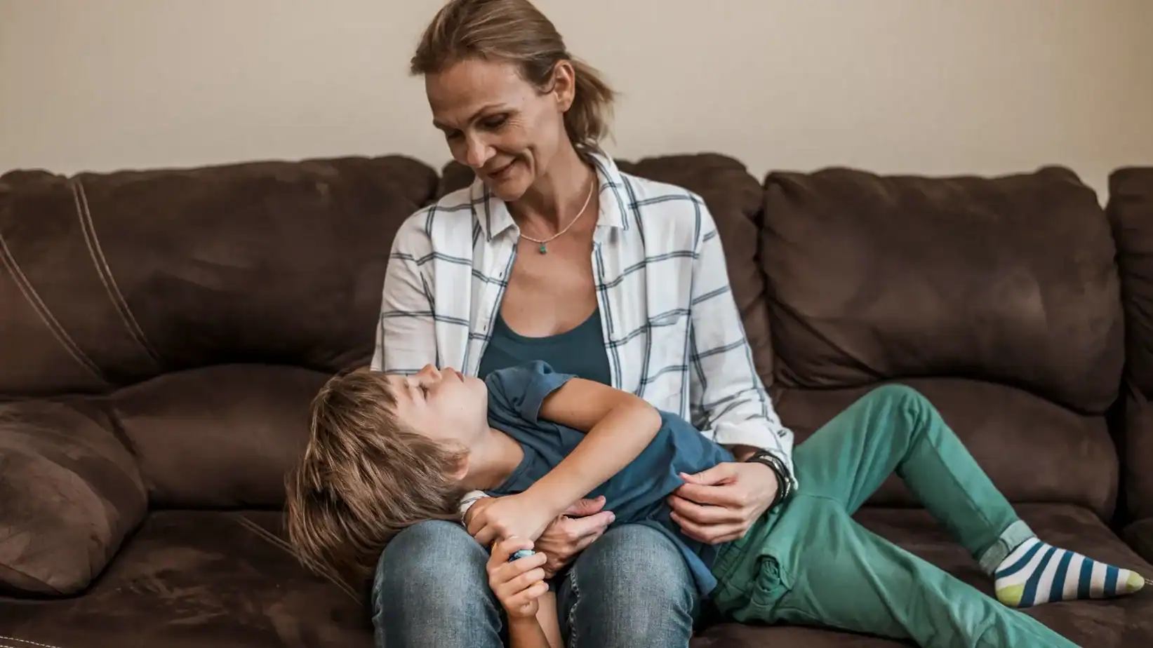 Madre y su hijo compartiendo un momento de conexión y afecto en el sofá de casa.