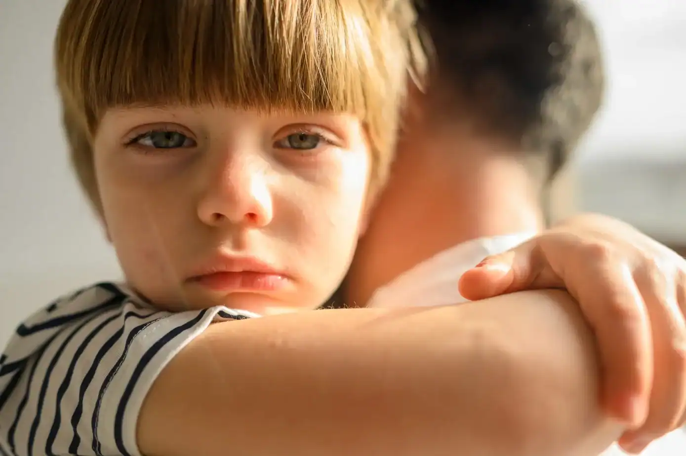 parentificación emocional Niño abrazado a un adulto con mirada seria y atenta, reflejando el peso emocional que sostiene en silencio.