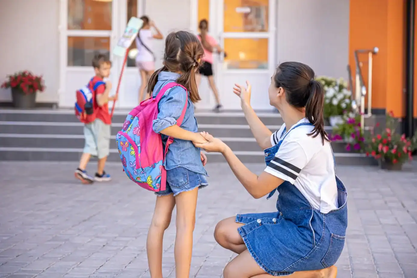 Inicio del curso escolar: niña entrando al colegio acompañada por su madre