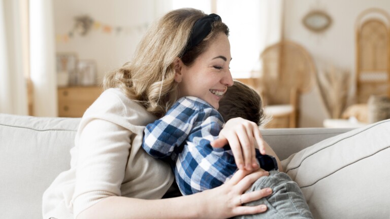 Inicio 4 Madre abrazando a su hijo pequeño en el sofá de casa, en un momento de calma