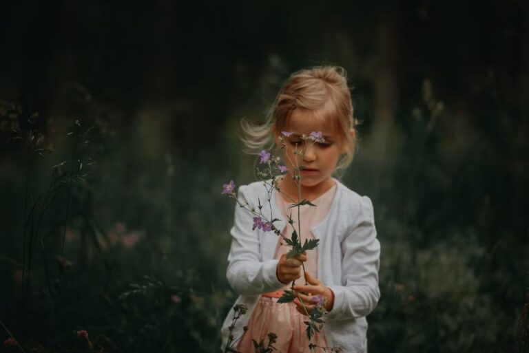 Inicio 4 Niña con cárdigan blanco observando con atención un ramillete de flores silvestres moradas