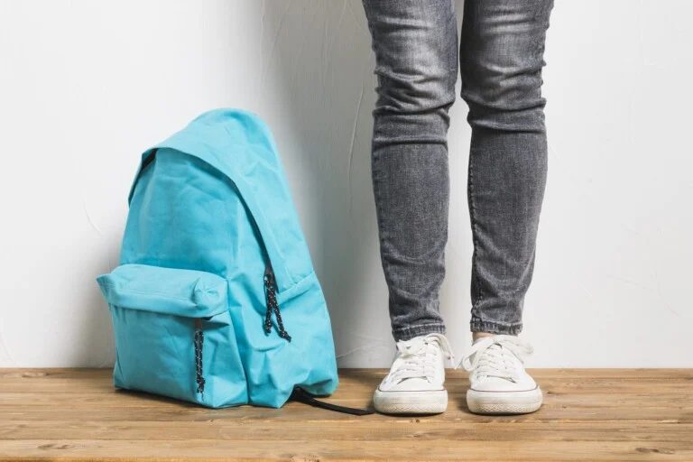 Inicio 6 La mochila en el pasillo, apoyada junto a unas zapatillas sobre el suelo de madera